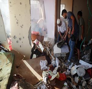 فلسطينيون يتفقدون موقع استهداف إسرائيلي لمبنى سكني في حي تل الهوى بمدينة غزة، حيث تناثرت مقتنيات السكان بين الأنقاض في أعقاب القصف.